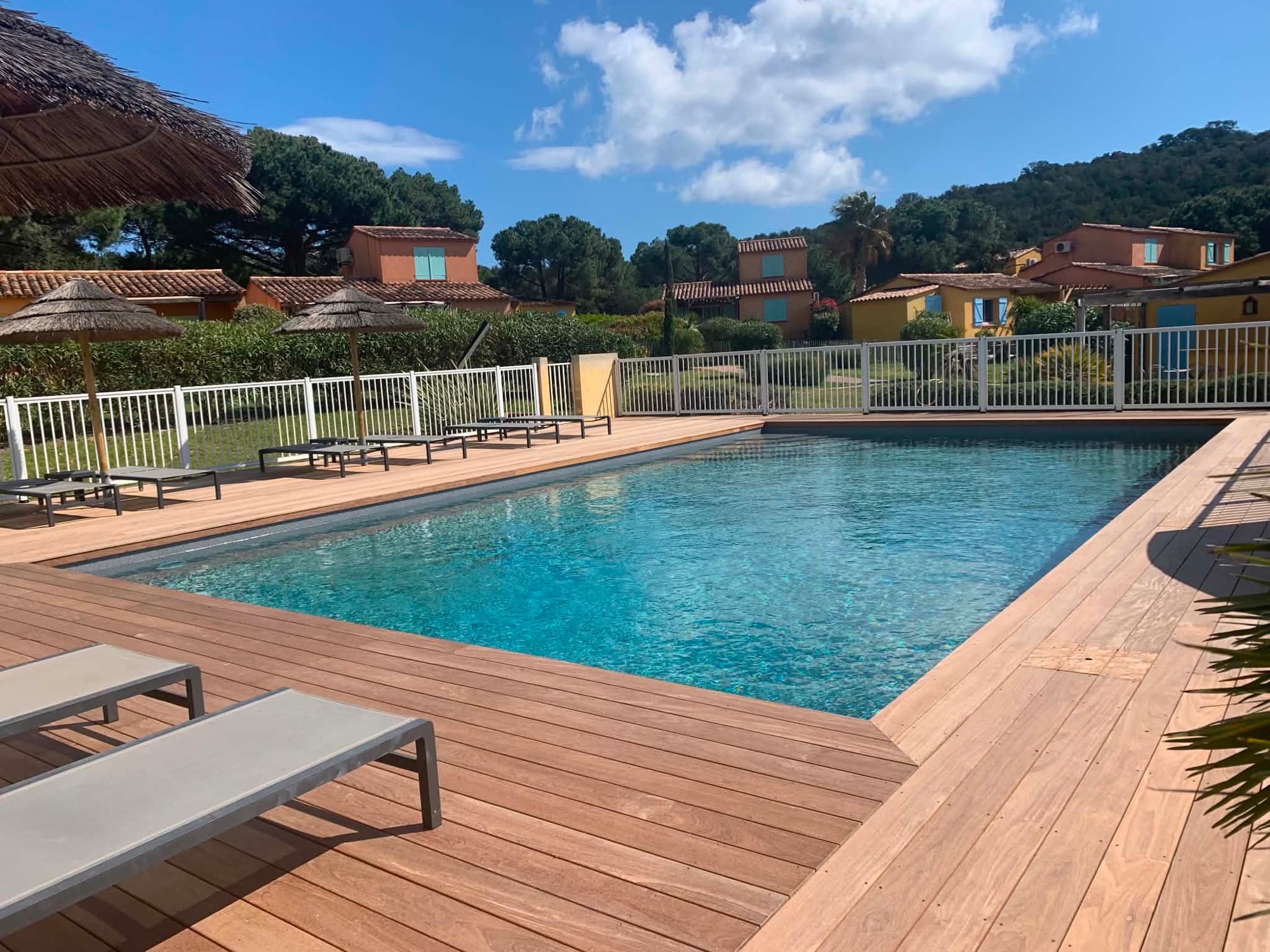 Piscine de la résidence Les Palmiers avec transats et parasols en paille