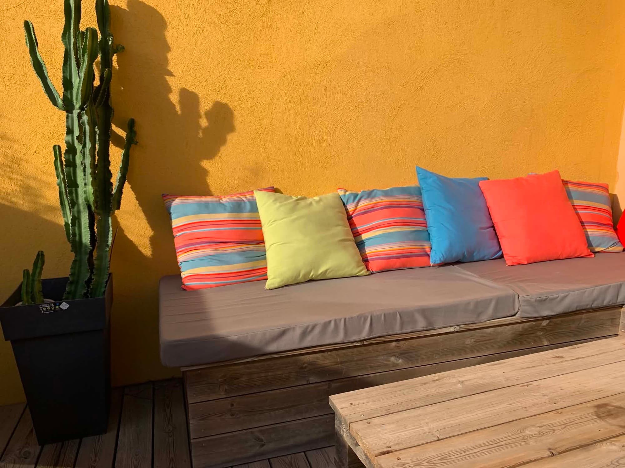 Terrasse de la Villa Dypsis en journée avec table à manger et chaises colorées