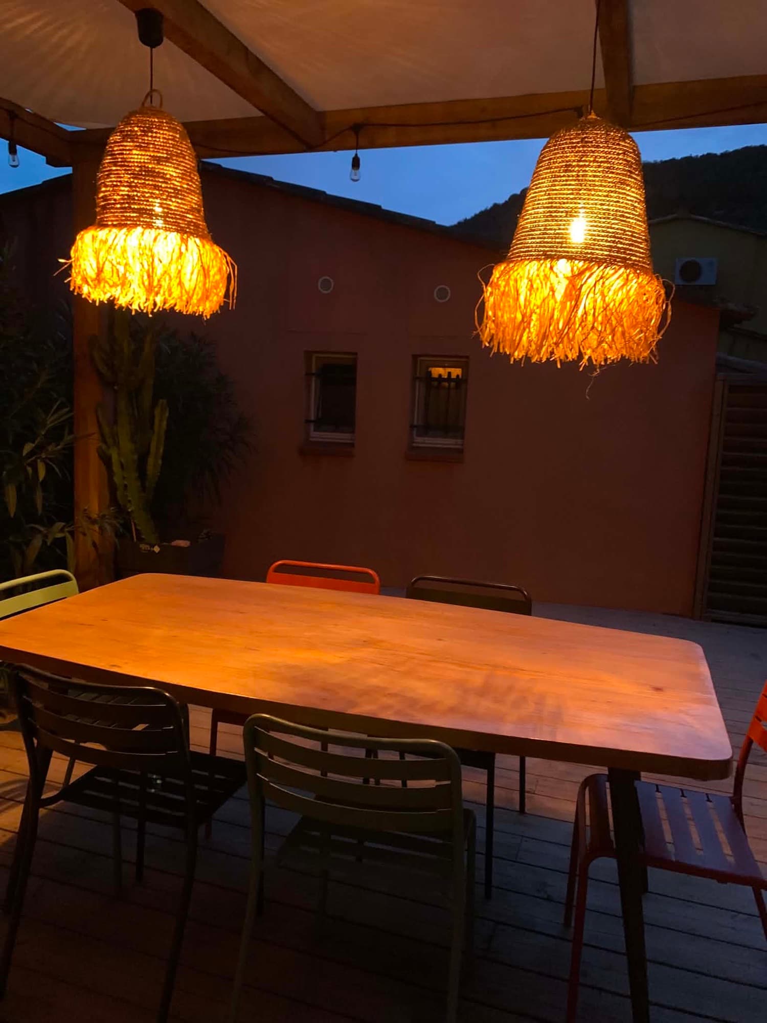 Terrasse de la Villa Dypsis en soirée, table dressée sous les suspensions lumineuses